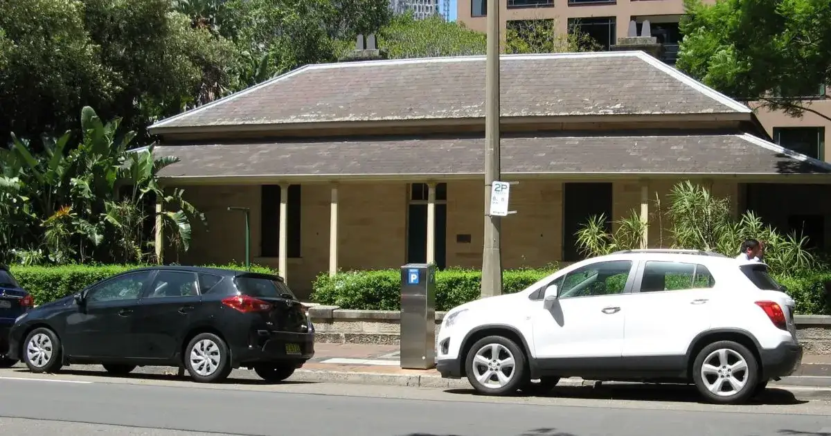 A white and a black car parked outside a building in Parramatta